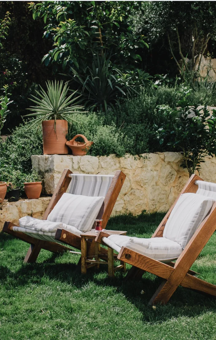 Outdoor lounge chairs in a landscaped backyard garden setting.