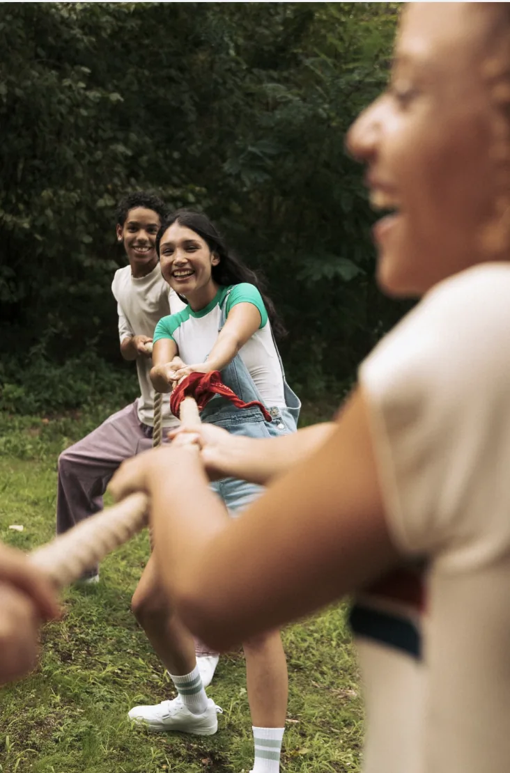 Young people playing tug-of-war outdoors, representing partnership momentum.